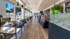 Un café moderno con una barra larga, zona de estar y grandes ventanales.
