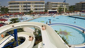 Parque acuático con múltiples toboganes y piscinas, rodeado de edificios de hotel.