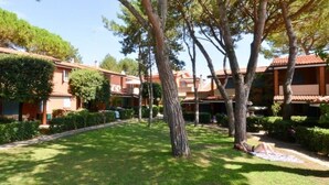 A courtyard with multiple buildings, a lawn, and trees.