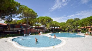 A swimming pool area with multiple pools, surrounded by buildings and trees.