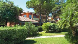 A two-story building with a red-tiled roof, surrounded by lush greenery and trees.