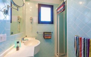 Une salle de bain équipée d’un lavabo, d’un miroir, d’un porte-serviettes et d’une douche.