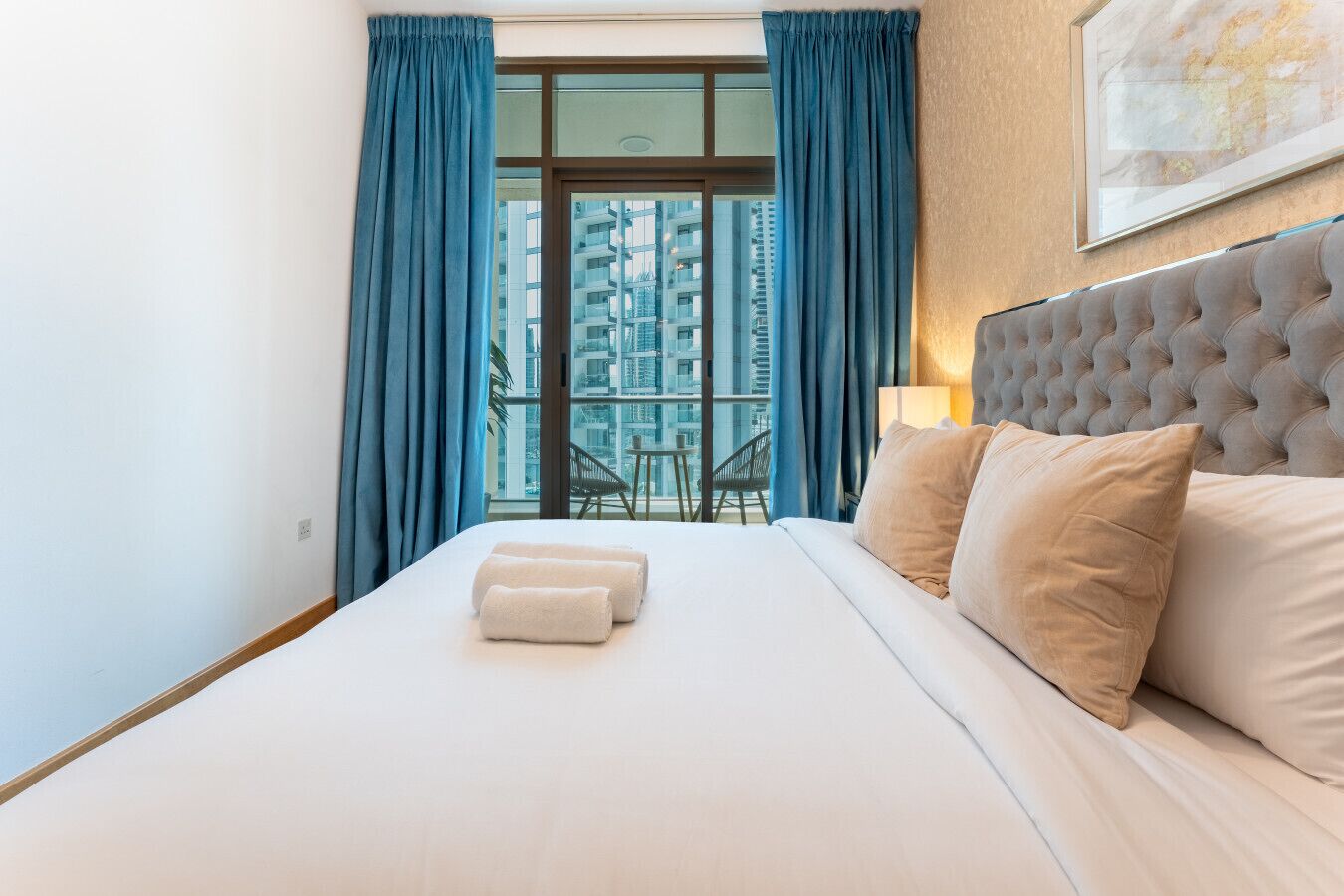 Une chambre d’hôtel avec un grand lit, une tête de lit, une fenêtre avec des rideaux et une vue sur des immeubles.