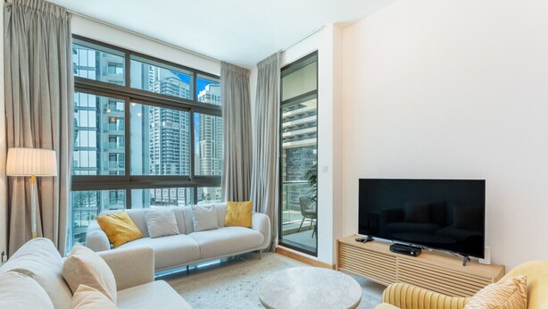 A modern living room with a sofa, a round coffee table, and a flat-screen TV.