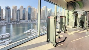 A gym with exercise equipment and a view of a city skyline and water.