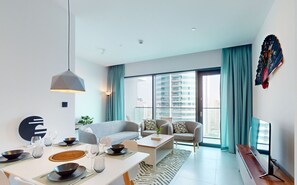 A modern living room with a dining area, large windows, and a city view.