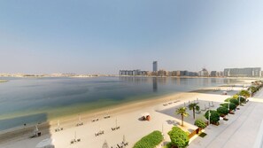 Um hotel à beira-mar com vista para a praia, areal arenoso e uma fileira de palmeiras.