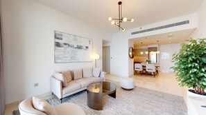 A modern living room with a sofa, coffee table, and a dining area with chairs and a table.