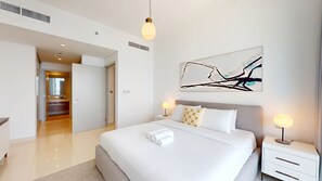 Een moderne hotelkamer met een groot bed, nachtkastjes, een wanddecoratie met abstracte kunst en een zichtbare badkamer.