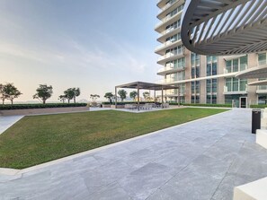 A modern building with a flat roof, large windows, and a paved courtyard with seating areas.