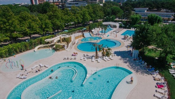Un resort con varias piscinas, tumbonas y un tobogán de agua.