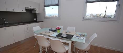 Una cocina moderna con armarios blancos, encimera negra y ventana con vistas a la ciudad.