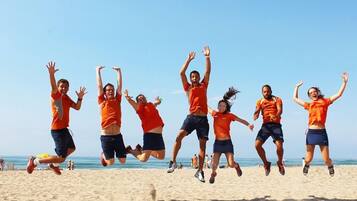A group of people jumping on a sandy beach.