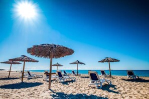 A beach with sun umbrellas and lounge chairs. - Vendrell Platja Bungalow für 4 Personen (Tarragona)
