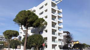 Un bâtiment moderne de couleur blanche, doté de nombreux balcons, d’un passage piéton et d’un panneau indiquant qu’il est interdit d’y entrer.