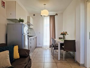 Una cocina compacta equipada con refrigerador, estufa y comedor con sillas y una mesa.
