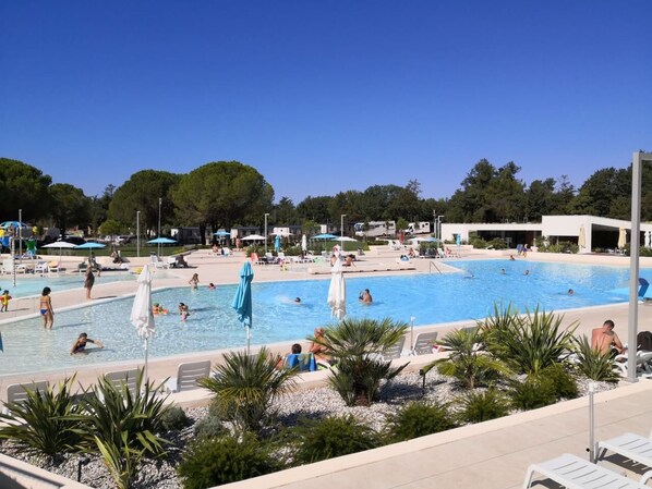Une grande piscine extérieure dotée de plusieurs couloirs de nage, entourée de chaises longues et de parasols.