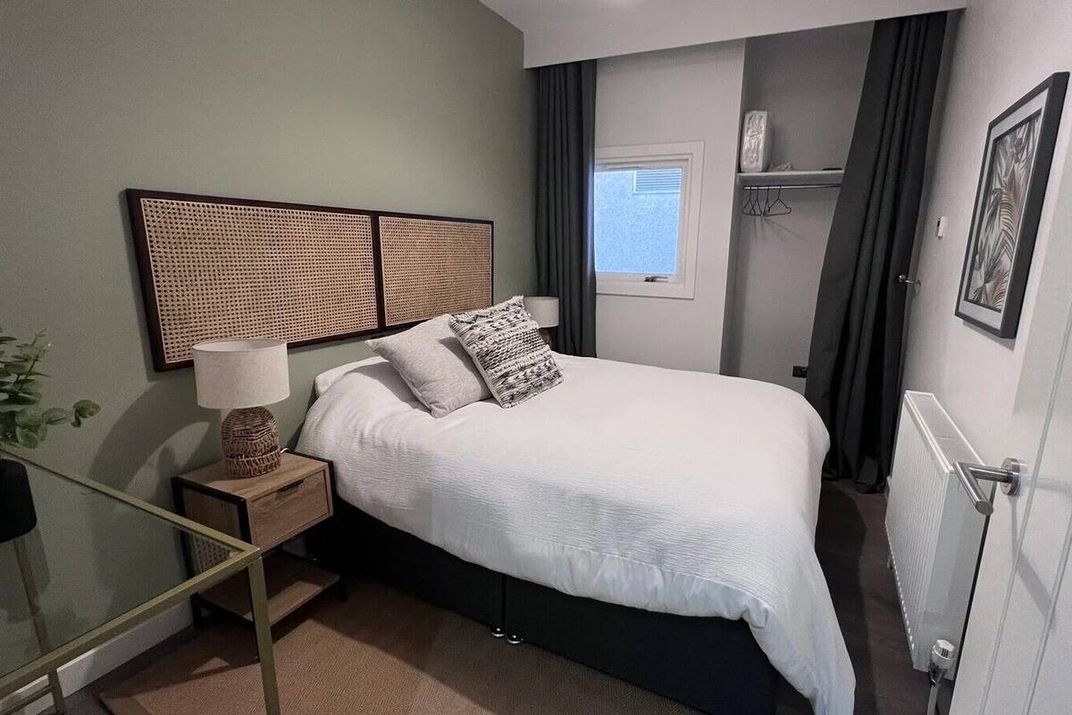 Une chambre à coucher bien rangée, avec un lit, une table de chevet, une lampe et une plante en pot.