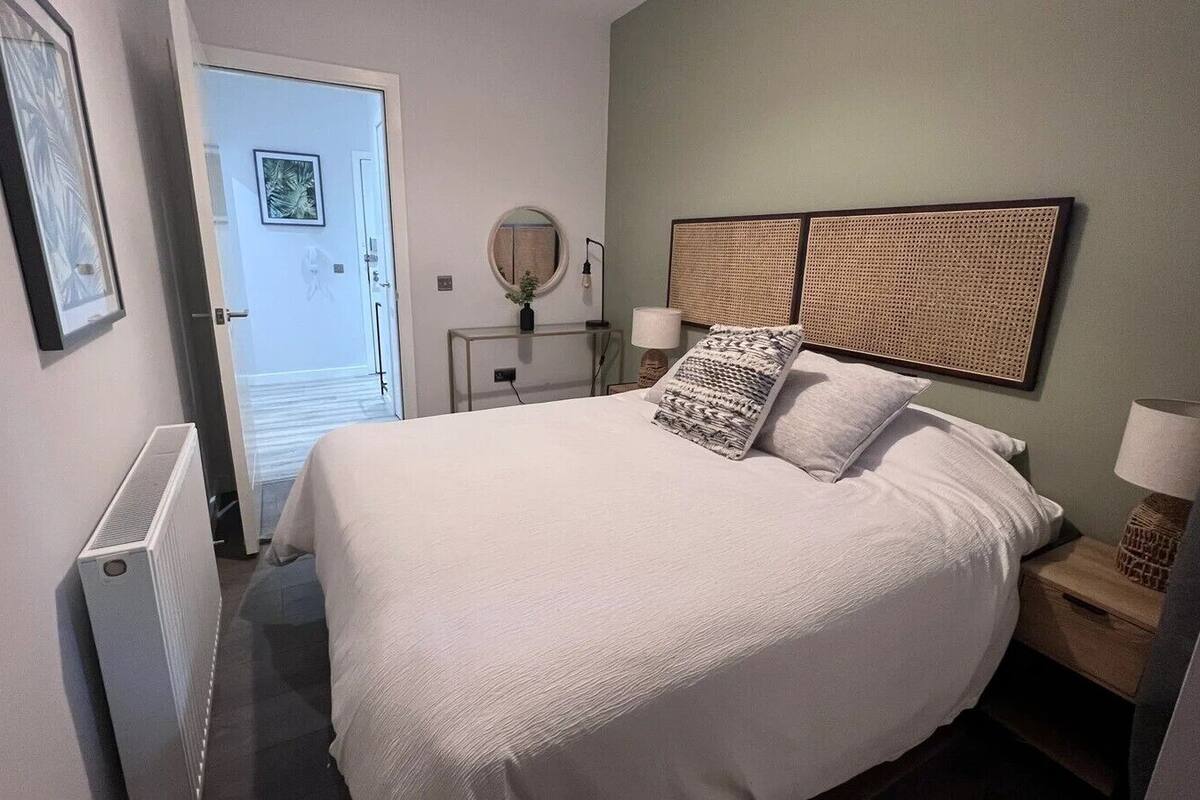 Une chambre à coucher bien rangée, avec un grand lit, des tables de chevet, un miroir et un radiateur.