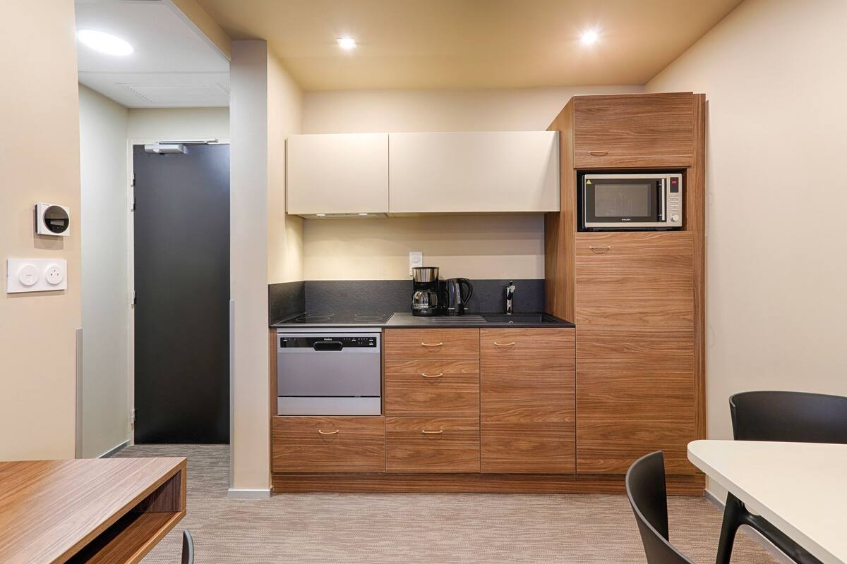 A compact kitchen with a dishwasher, microwave, and coffee maker.