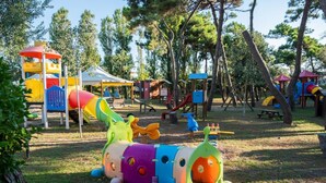 Um parquinho com diversas estruturas de lazer, incluindo um escorrega, balanços e um passeio de trem colorido.
