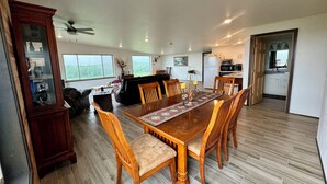 A spacious dining area with a large wooden table and chairs, a dark-colored sofa, and a cabinet with glass doors. - Ranch get away (Merrill)