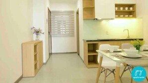 A modern kitchen with white cabinets, a dining table with chairs, and a small side table with a vase of flowers.