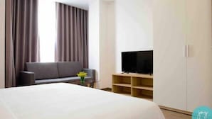 A modern hotel room with a large bed, a sofa, a TV, and a wardrobe.