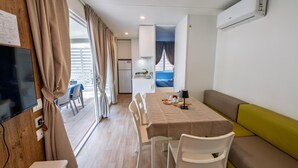 Une pièce moderne et bien éclairée, comprenant une table à manger, des chaises, un canapé et un téléviseur.