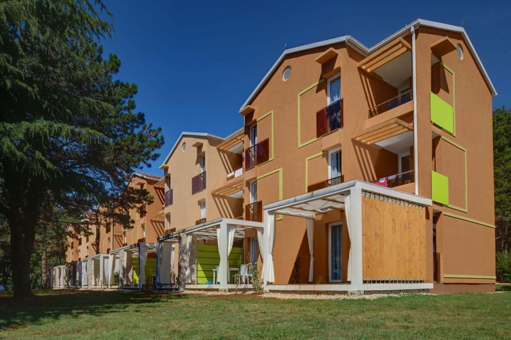 A row of modern multi-story buildings with balconies and covered outdoor seating areas.