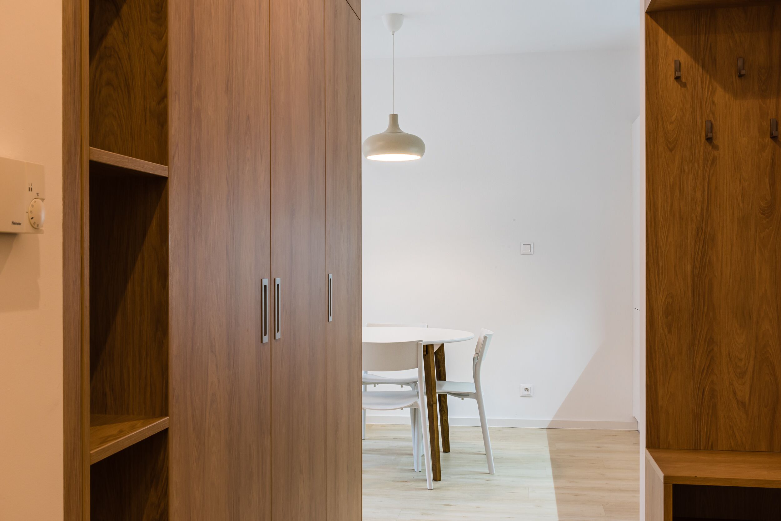 A room with wooden cabinets, a white dining table, and chairs.