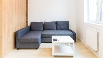 Ein modernes Wohnzimmer mit einem grauen Ecksofa, einem weißen Couchtisch und einem Holzschrank.