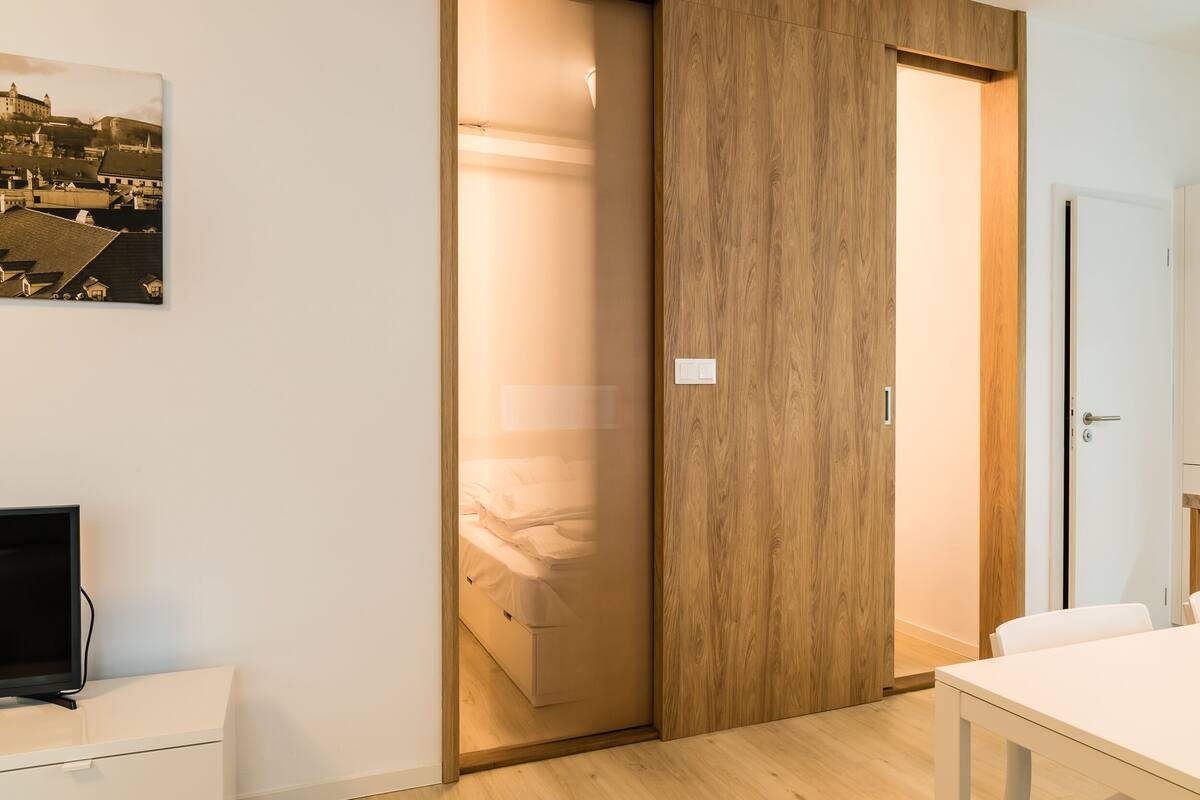 Una habitación moderna con una cama, un televisor y un armario de madera.