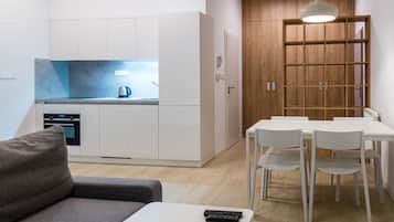 A modern kitchen with white cabinets, a blue backsplash, and a kettle on the counter.