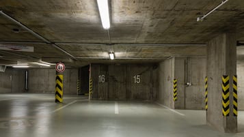 An underground parking garage with concrete walls, numbered parking spots, and caution signs.