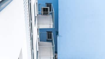 Un bâtiment à la façade bleue et doté d’un balcon blanc avec des garde-corps en métal.