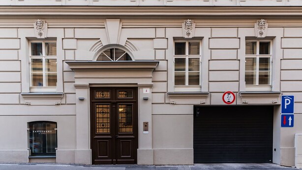 Un edificio con una puerta doble color marrón oscuro, una puerta de garaje y un letrero de estacionamiento.