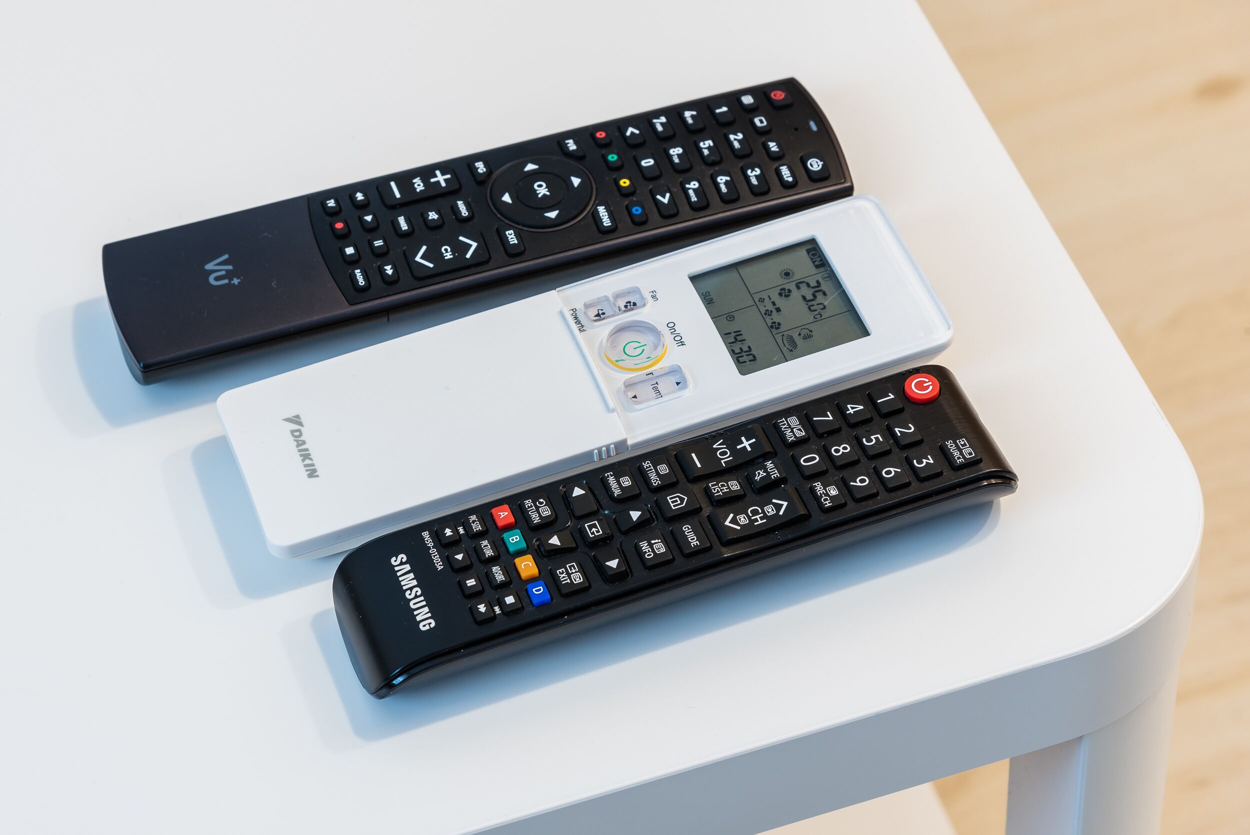Three remote controls on a white table.