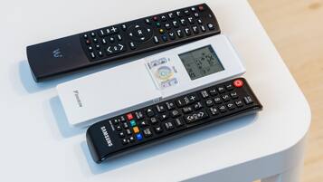 Three remote controls on a white table.