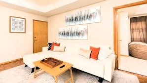 A modern living room with a white sofa, a wooden coffee table, and abstract wall art. - McAllen Majesty 4BR w Pool and Comfort (McAllen)