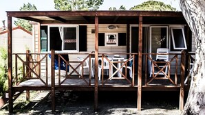 Una terraza de madera con barandilla, mesa y sillas.