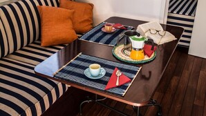 Ein gemütlicher Sitzbereich mit gestreiften Kissen, einem kleinen Tisch mit Tasse, Buch und Wasserkocher.