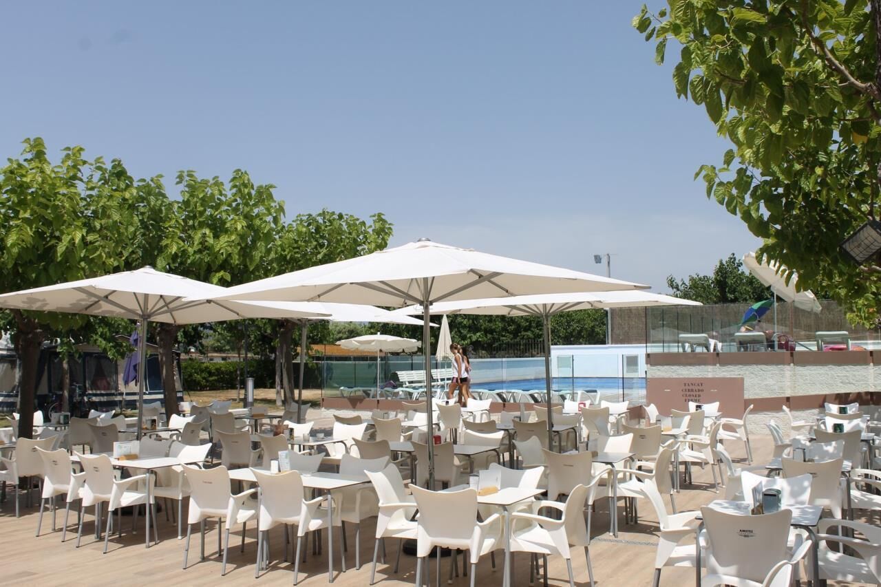 Buiten zitplaatsen met parasols, een zwembad en een heldere lucht.