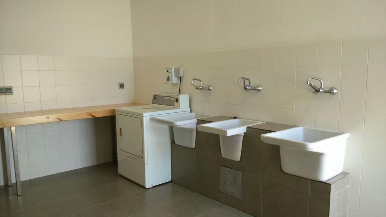 Ein helles, modernes Badezimmer mit Waschmaschine, zwei Waschbecken und einer Holzausstattung.