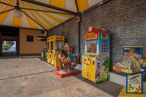 A row of colorful arcade machines under a yellow and white striped canopy.