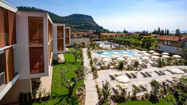 Ein modernes Hotel mit Poolbereich, Sitzgelegenheiten im Freien und Blick auf die umliegende Landschaft.
