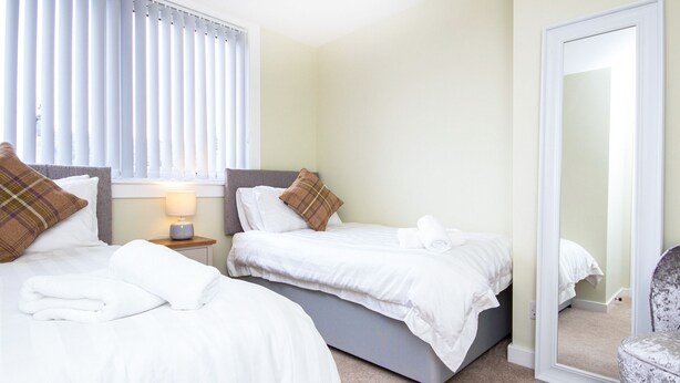 Une chambre d’hôtel avec deux lits, une table de chevet avec une lampe, un miroir et une chaise.