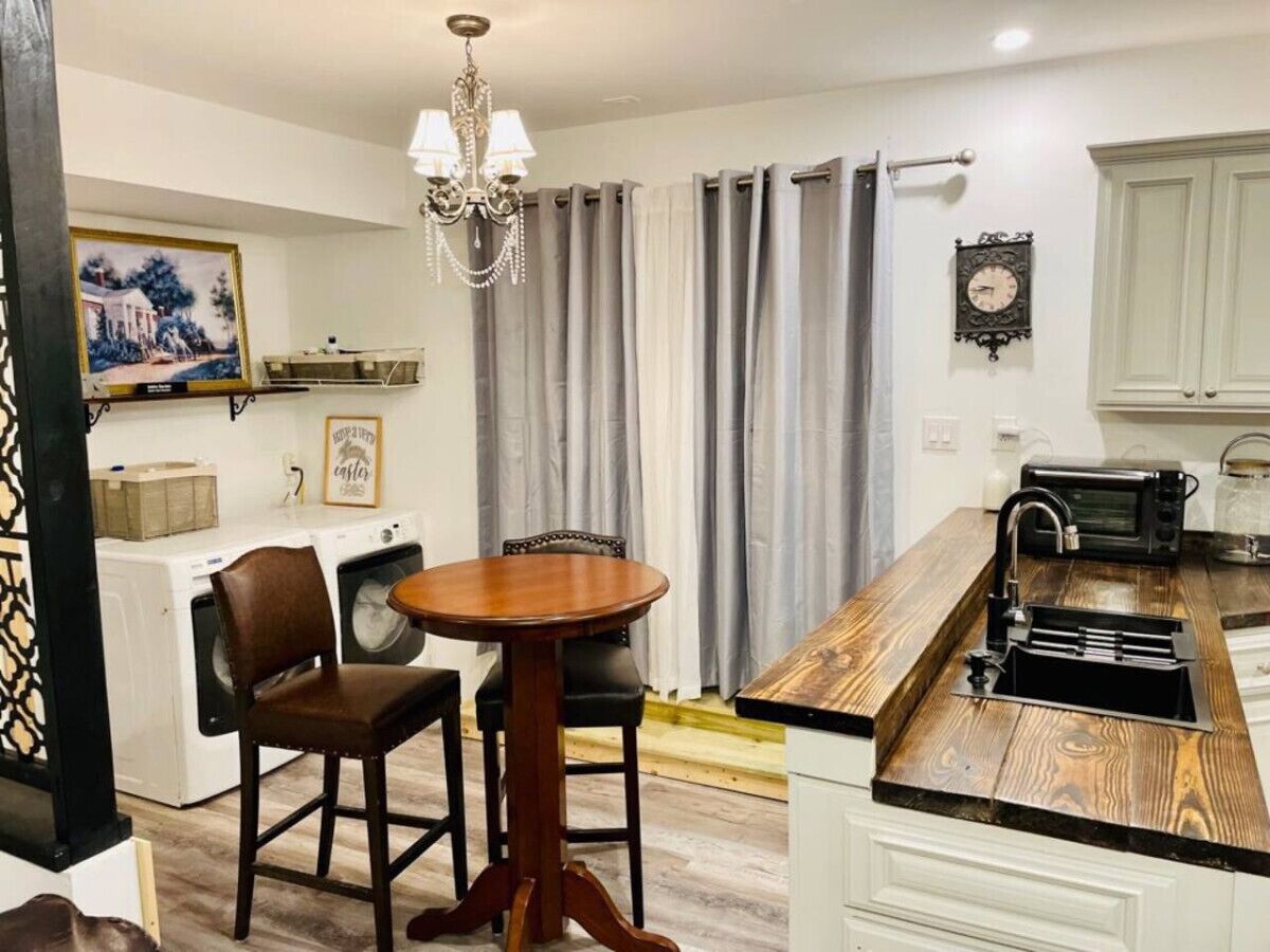Cocina compacta con comedor, lavadora, candelabro y un reloj en la pared.