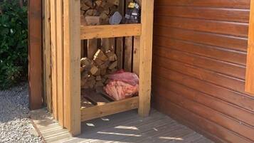 A wooden structure with a sloped roof, a wooden bench, and a stack of firewood.