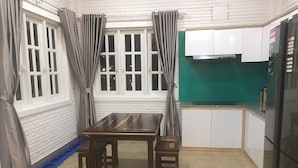 Cocina compacta con una mesa y sillas, paredes de ladrillo blanco y salpicadero verde.